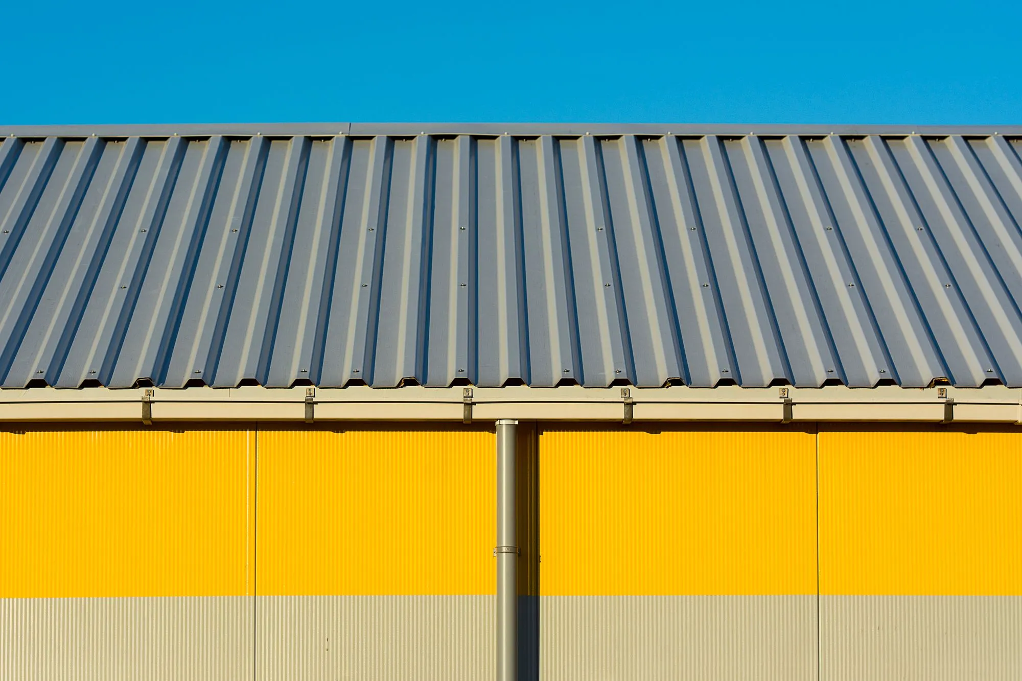 Building with a profiled roof and yellow panel walls