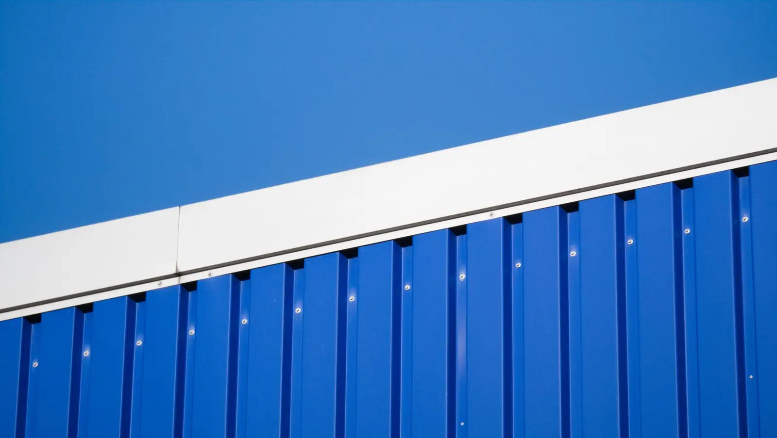 Blue profiled metal wall under a clear sky